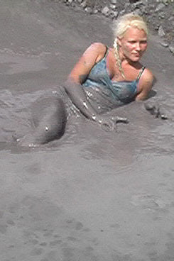 Person partially submerged in a muddy pit with a copyright notice at the bottom.
