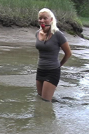 Woman standing in shallow water near a grassy bank