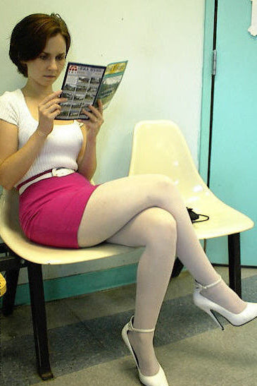 Woman sitting on a chair reading a magazine in a room with a blue wall.