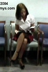 Woman sitting in a chair with a book, surrounded by chairs in a room.