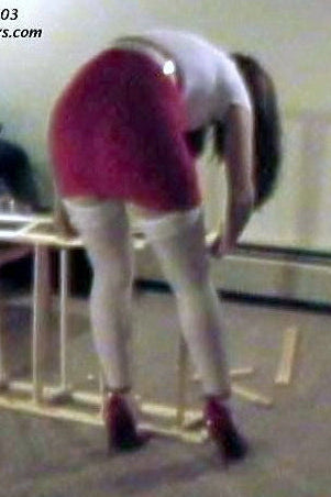 Person assembling a piece of furniture in a room with a television and couch.