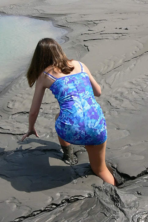 Person in a blue swimsuit standing on a muddy beach