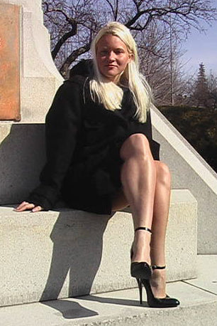 Woman in a black dress sitting on a monument with a plaque in the background
