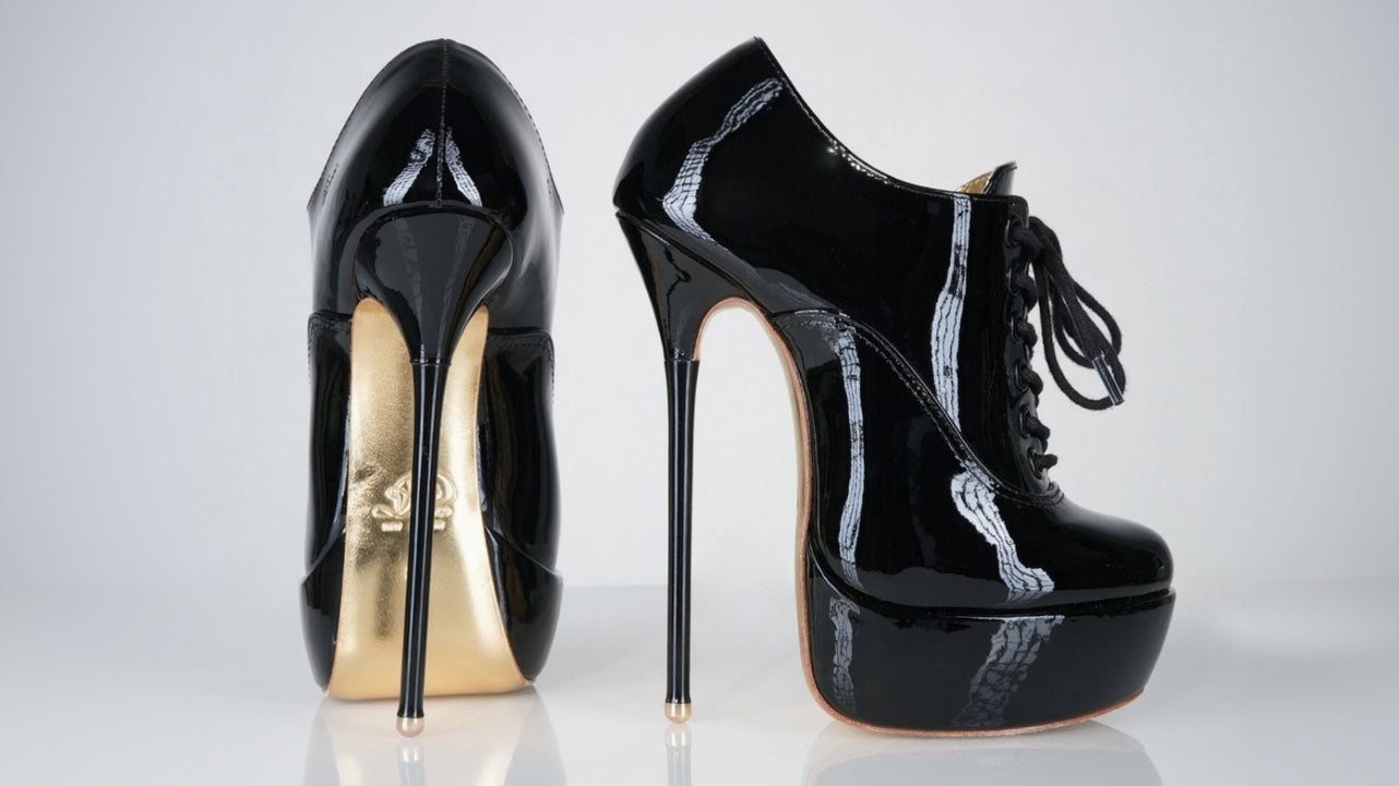 Black high-heeled shoes with gold soles on a white background