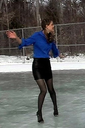Person ice skating on a frozen pond with snow-covered trees in the background