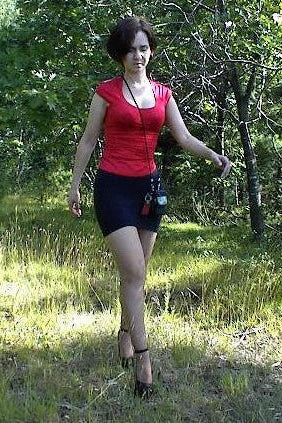 Woman in a red top and black skirt walking through a forest