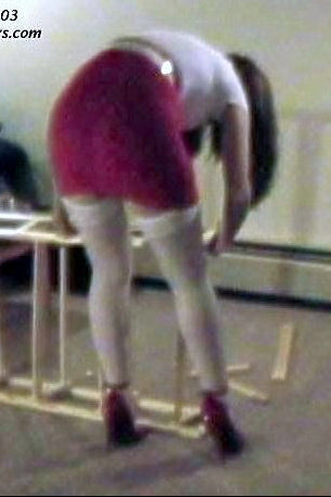 Person assembling a piece of furniture in a room with a television and couch.